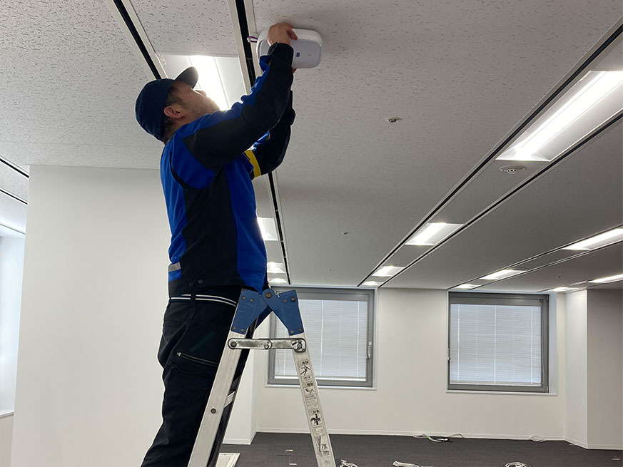 脚立に乗って作業をする従業員